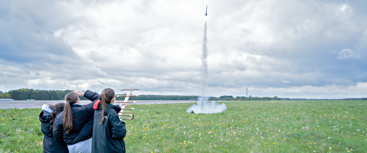 a group of three students launching a cansat into air