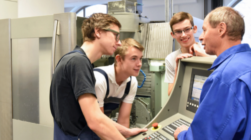 STEM Ambassador with three students using a manufacturing console